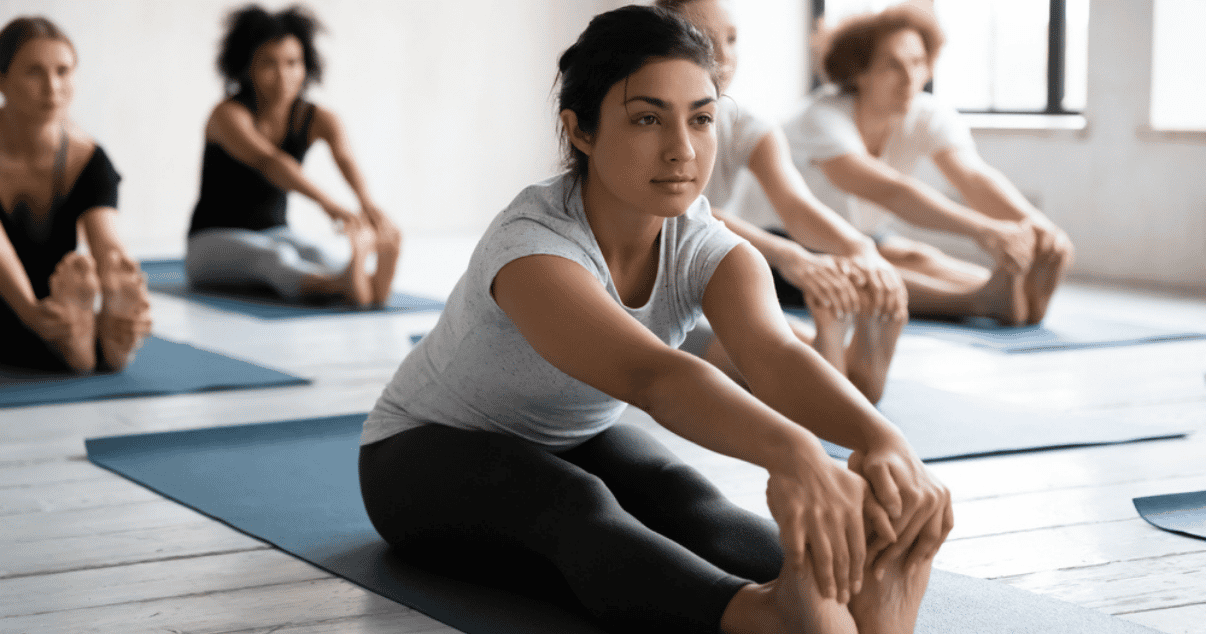 Woman touching her feet at a gym class which might cause athletes foot